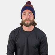 Cold-weather beanie with pom, navy knit with orange BLACKSTRAP stripe worn by a model