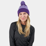 Purple pom beanie with white logo stripe; model wearing the beanie