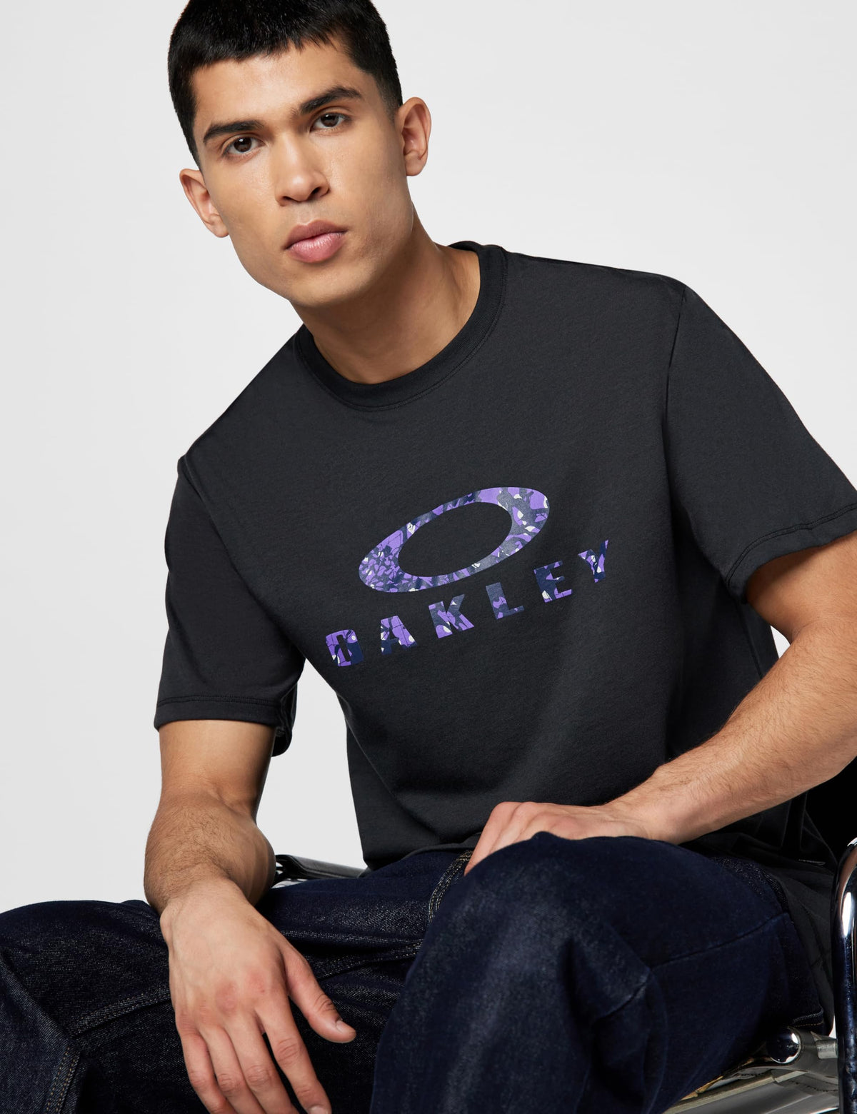 Black crew-neck T-shirt with purple Oakley O logo print across the chest.